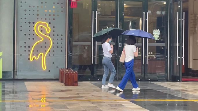 雨天两个女孩撑伞行走回家背影