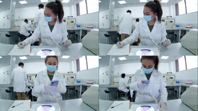 在生物实验课上，一名女生在显微镜下观察样本，用笔记和智能手机上的视频记录一切