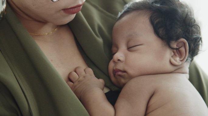 亚洲妈妈怀着非洲泰国宝宝睡在胸前