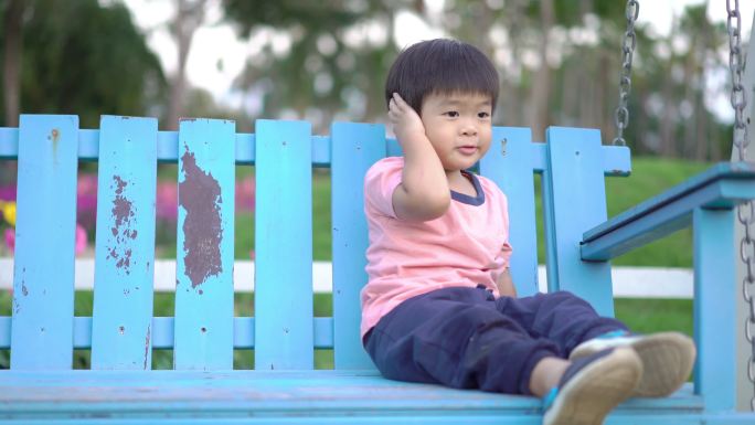 公园里蓝色秋千上的亚洲男孩