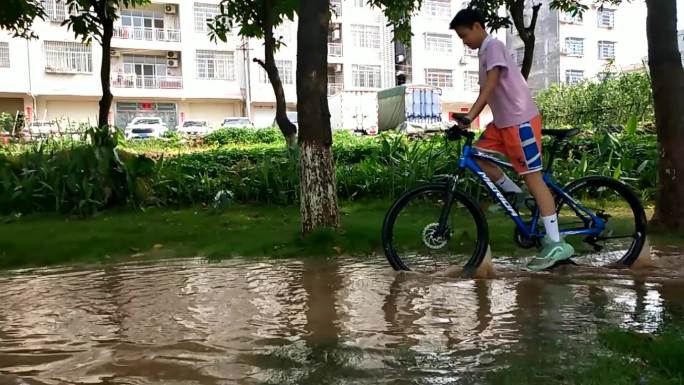 少年在有水的草地骑自行车骑玩自行车车技