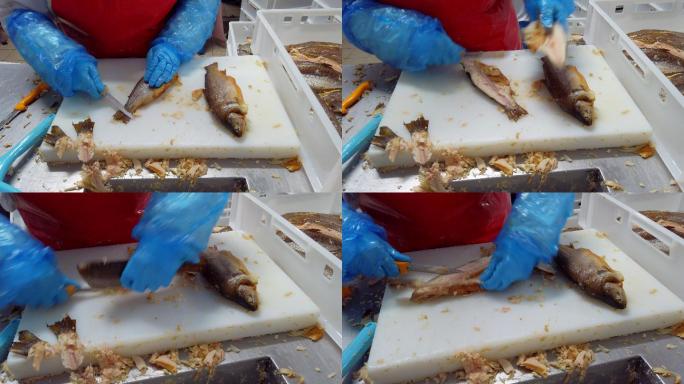 一名工人正在一家工业鱼类包装设施中用鱼片刀清理菲力鲑鱼和鳟鱼的包装
