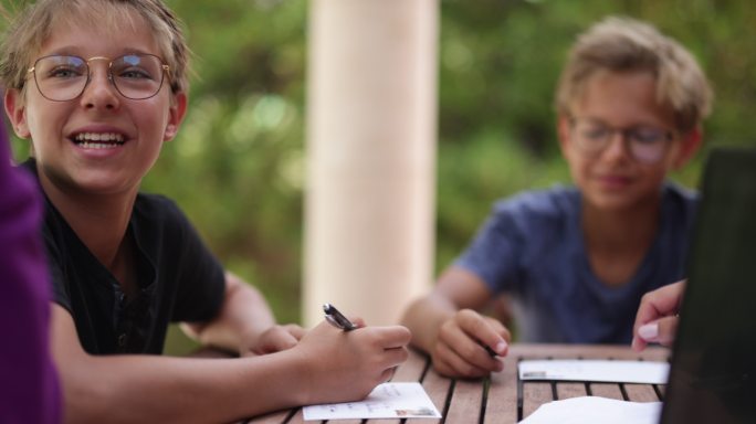 青少年坐在后院的桌子旁写明信片