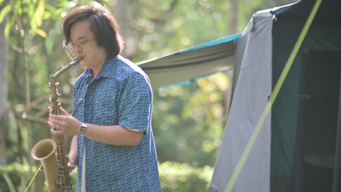 早上，亚裔中国萨克斯管演奏家在露营帐篷前演奏