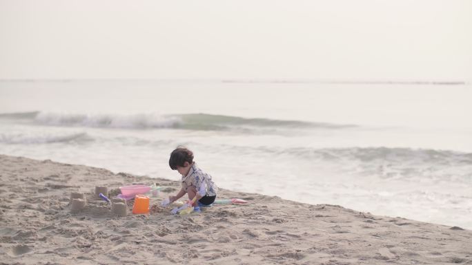 可爱的男孩在沙滩上玩沙子，玩得很开心。
