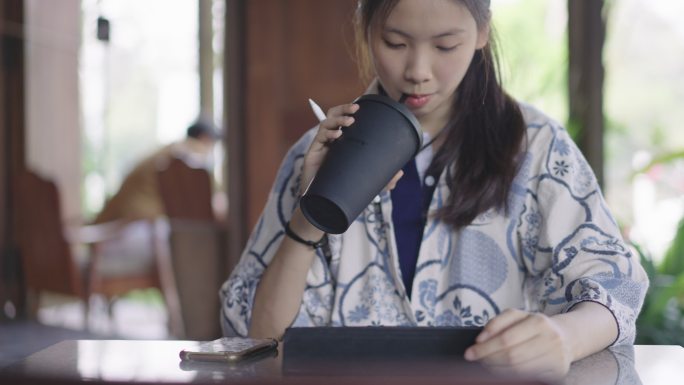 年轻的亚洲女性饮用环保型可重复使用的咖啡杯
