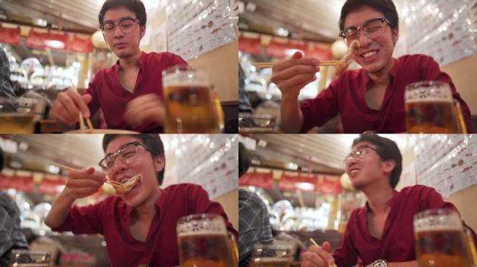 亚洲男子在日本餐厅izakaya享受美食