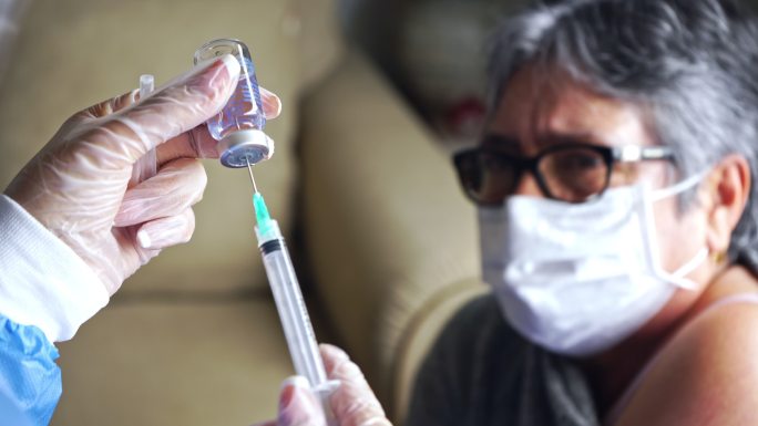 女医生在家为一位老年妇女接种疫苗