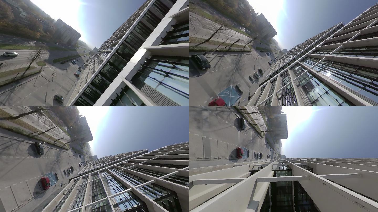 360度视图。蓝天映衬下的现代玻璃建筑的城市景观。FPV无人机向上和内部飞行
