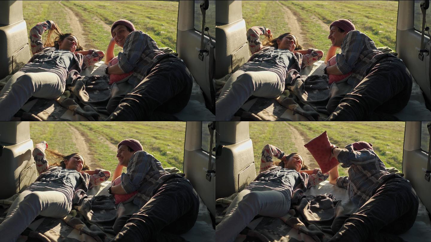 一对年轻夫妇躺在露营车的尾门上