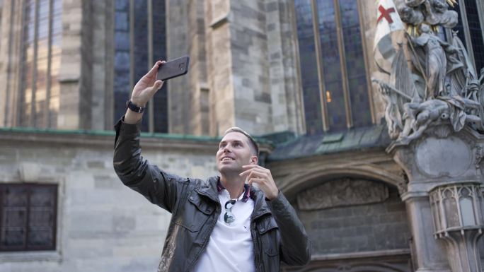 现代男性游客在维也纳圣斯蒂芬斯大教堂前用手机自拍