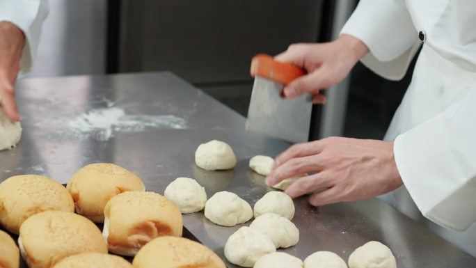 特写镜头：在前面的烤箱中烤面包，厨师在成型前将面团分成相同大小，厨师揉捏和准备面团，在商业面包房厨房