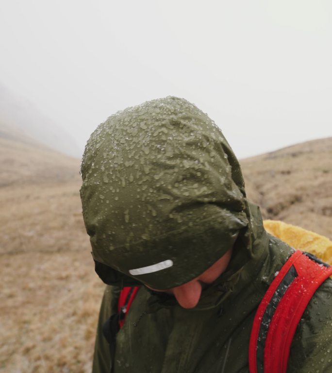 男性徒步旅行者在雨夹雪/暴雨期间观望