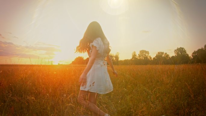 落日时分，一位穿着白色连衣裙的美丽年轻女子在草地上旋转