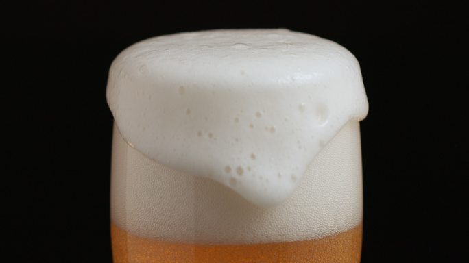 啤酒溅到了玻璃杯的边缘，留下了泡沫的痕迹