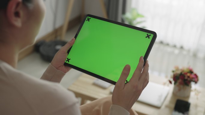 女性看着绿色屏幕的数字平板电脑