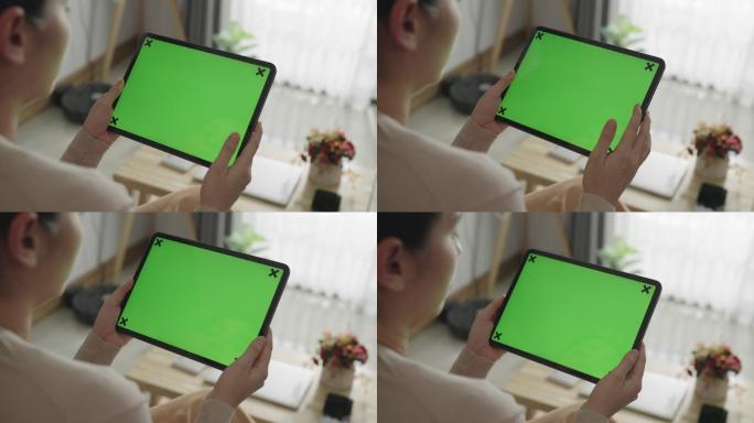 女性看着绿色屏幕的数字平板电脑
