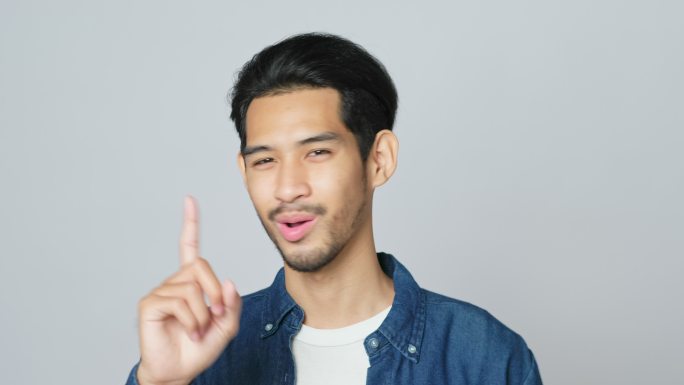 一名年轻的亚洲男子站在灰色背景下，脸上露出失望的表情，分辨率为4k