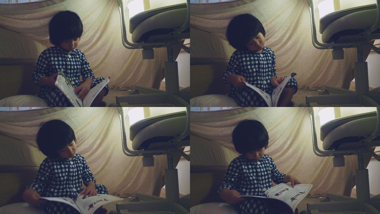 亚洲男孩在毛毯下用手电筒读童话