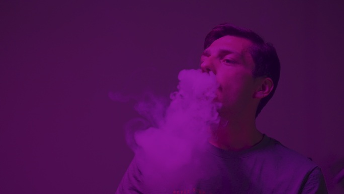一个年轻人的肖像，在房间里吹着一叠烟，被紫光照亮