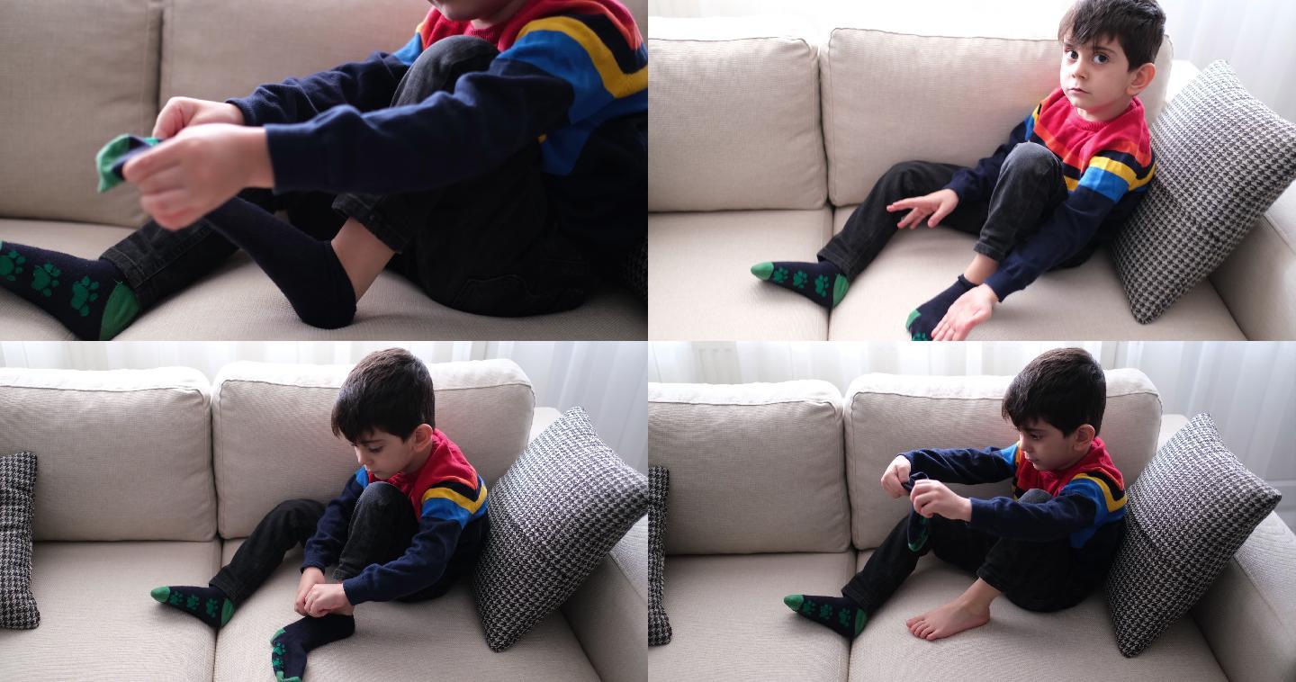 可爱的小男孩试着穿袜子。