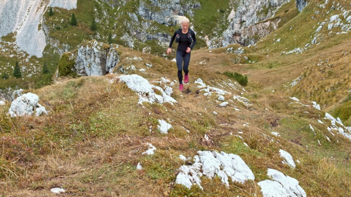 女运动员在山坡上的草地上跑步