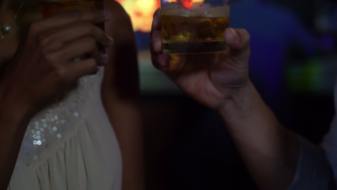 一对面目全非的情侣在酒吧用威士忌敬酒的特写镜头