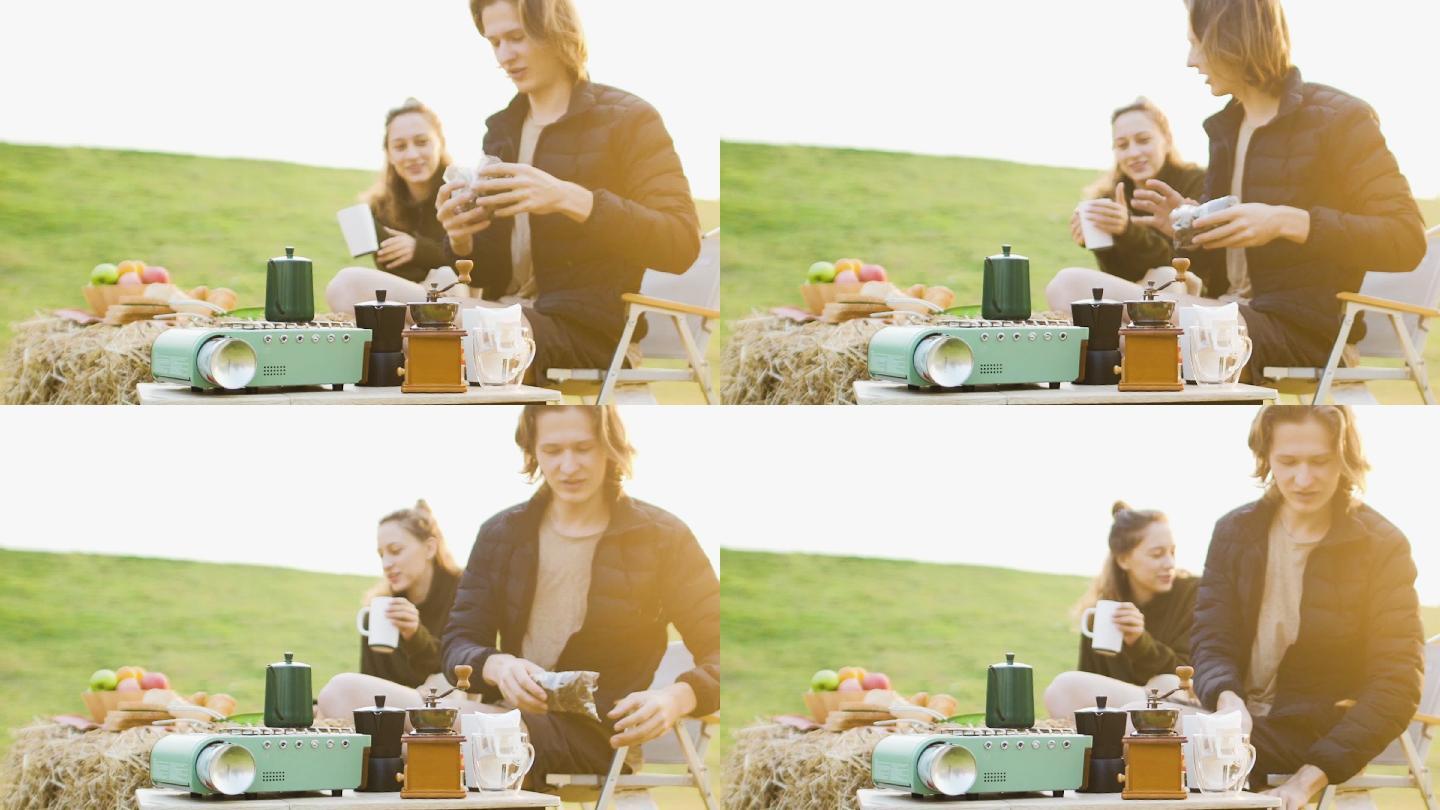 美丽的白人白人年轻夫妇在日出时分野餐。男人和女人喝咖啡和热茶，背景是草原和山脉。