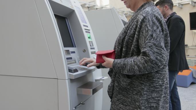 高级女性使用ATM，手持镜头