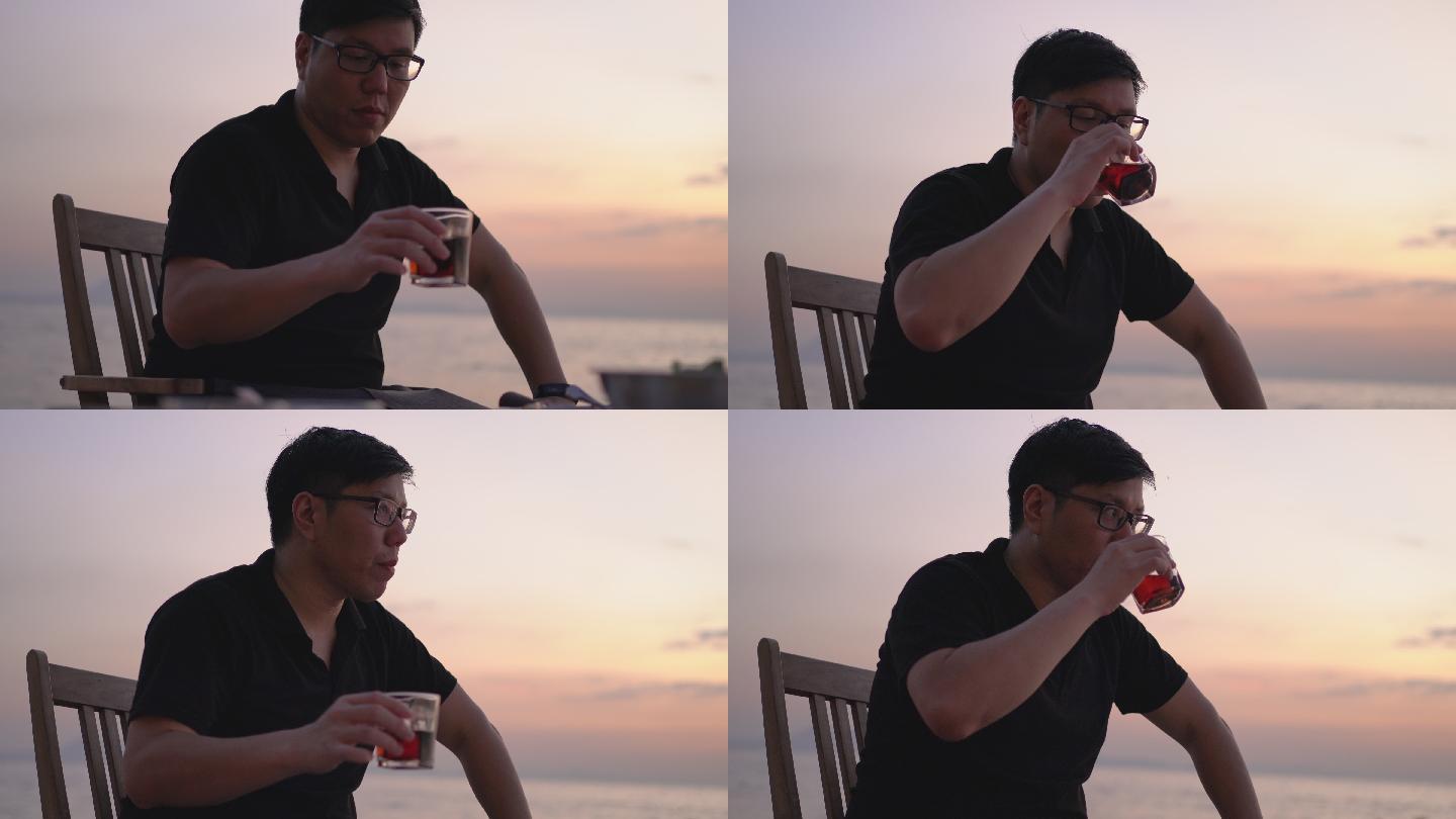 亚洲男人在海边和风边喝酒