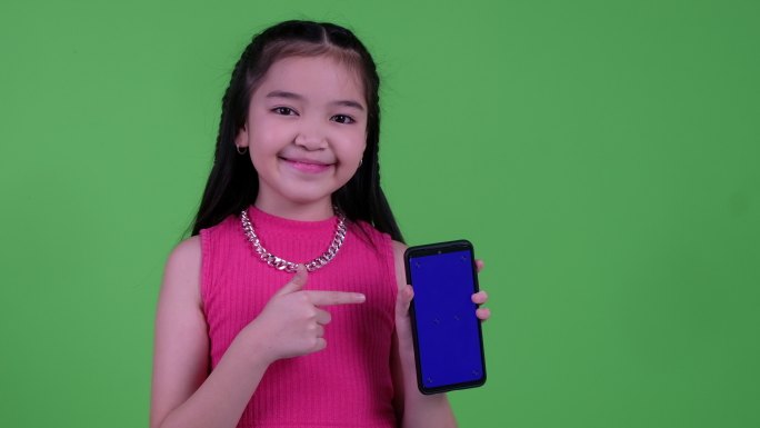 女孩用手指指着绿色屏幕上的智能手机