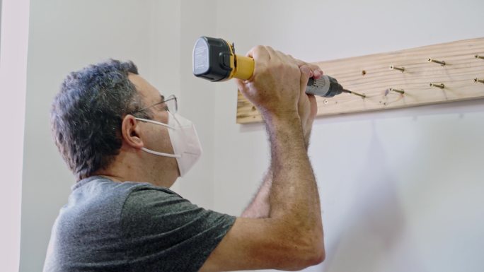 在自己的房子里，为了厨房改造，在墙上拧上一块木头的特写镜头