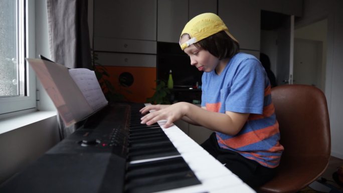 男孩在合成器和键盘上演奏音乐