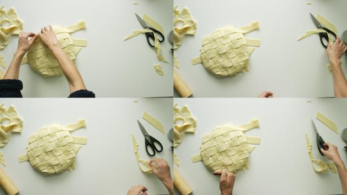 一个女人的手在头顶上将一条条糕点面团编织在一起，形成一个格子状的馅饼表层，然后用剪刀修剪边缘