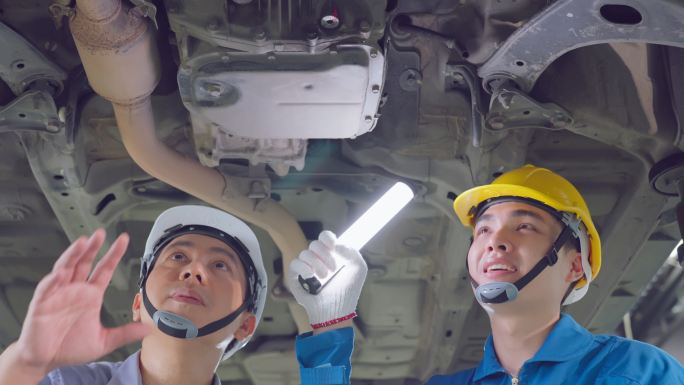 两名亚裔汽车技师戴着面具，在汽车修理厂工作。车辆服务经理团队男员工查看车辆状况，检查和维护，以便在车