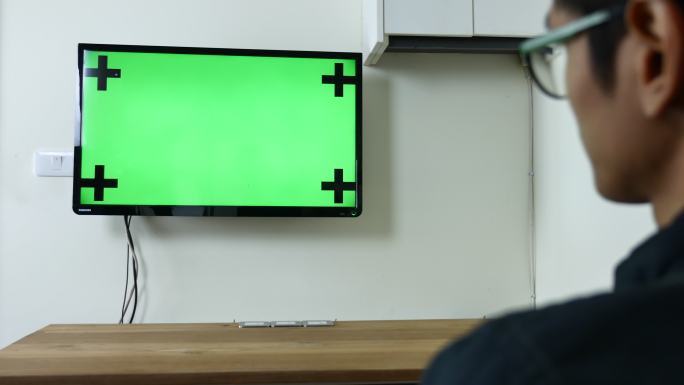 男子观看绿色模拟屏幕电视