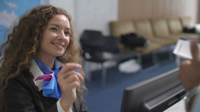 在机场值机柜台使用电脑和工作的高加索女性航空公司员工面带微笑