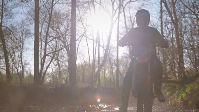 摩托车越野赛骑手在森林小道上踩水坑