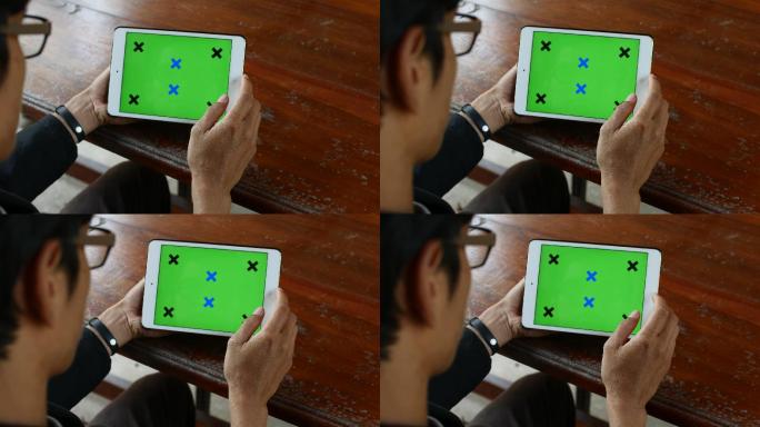 年轻人在木桌上使用数字平板电脑绿色屏幕，肩上视图，4K（UHD）
