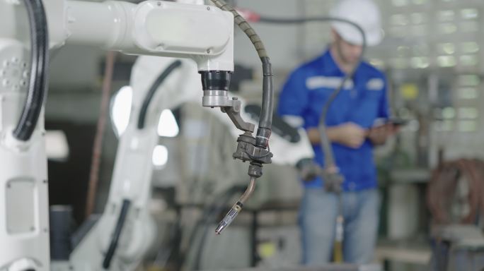 智能工厂工业中的年轻男性工程师检查和控制焊接机器人自动臂机。机器人、科学技术、工业、自动化、机器人概