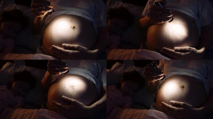 怀孕的女性在晚上睡觉时用手电筒或手电筒照子宫。
