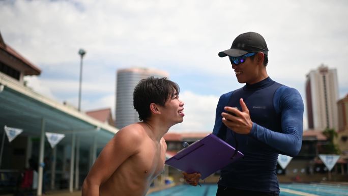 快乐亚裔中国私人教练分析显示他的学生在秒表上打破记录教育培训班结束后游泳池边的游泳考试成绩