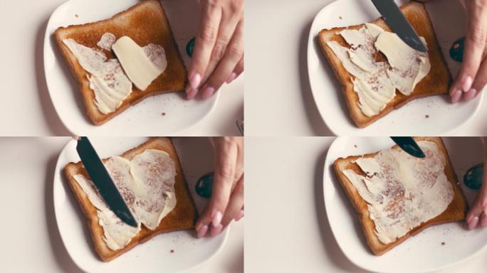 女性在面包片上涂黄油和果酱的手