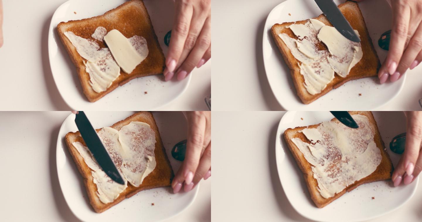 女性在面包片上涂黄油和果酱的手
