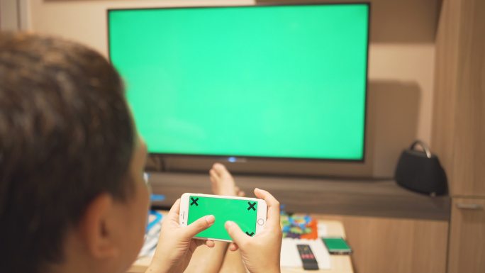 一个玩智能手机看电视的男人，绿色屏幕