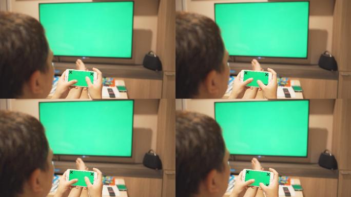 一个玩智能手机看电视的男人，绿色屏幕