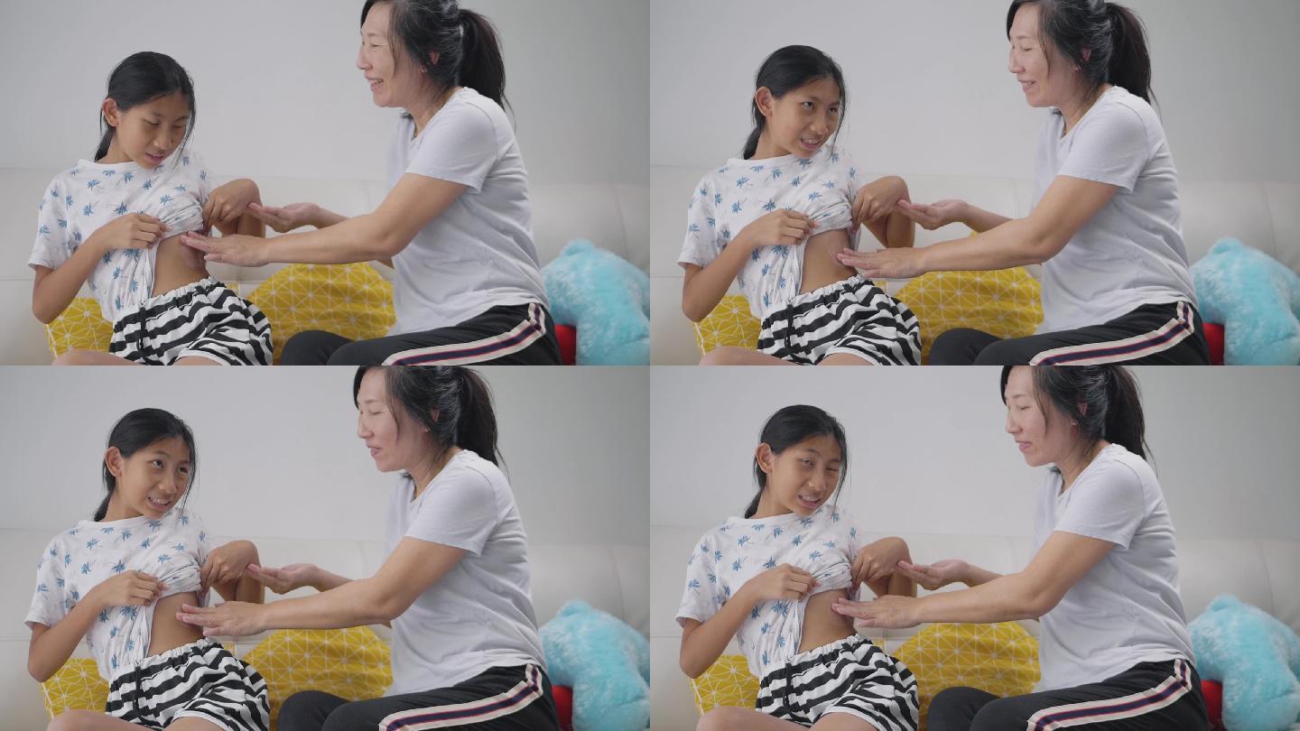 亚洲母亲为女儿在家沙发上应用过敏药，健康和药物的生活方式理念。