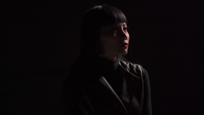 低调的亚洲中国女性时装模特在工作室肖像画中态度冷静黑色背景