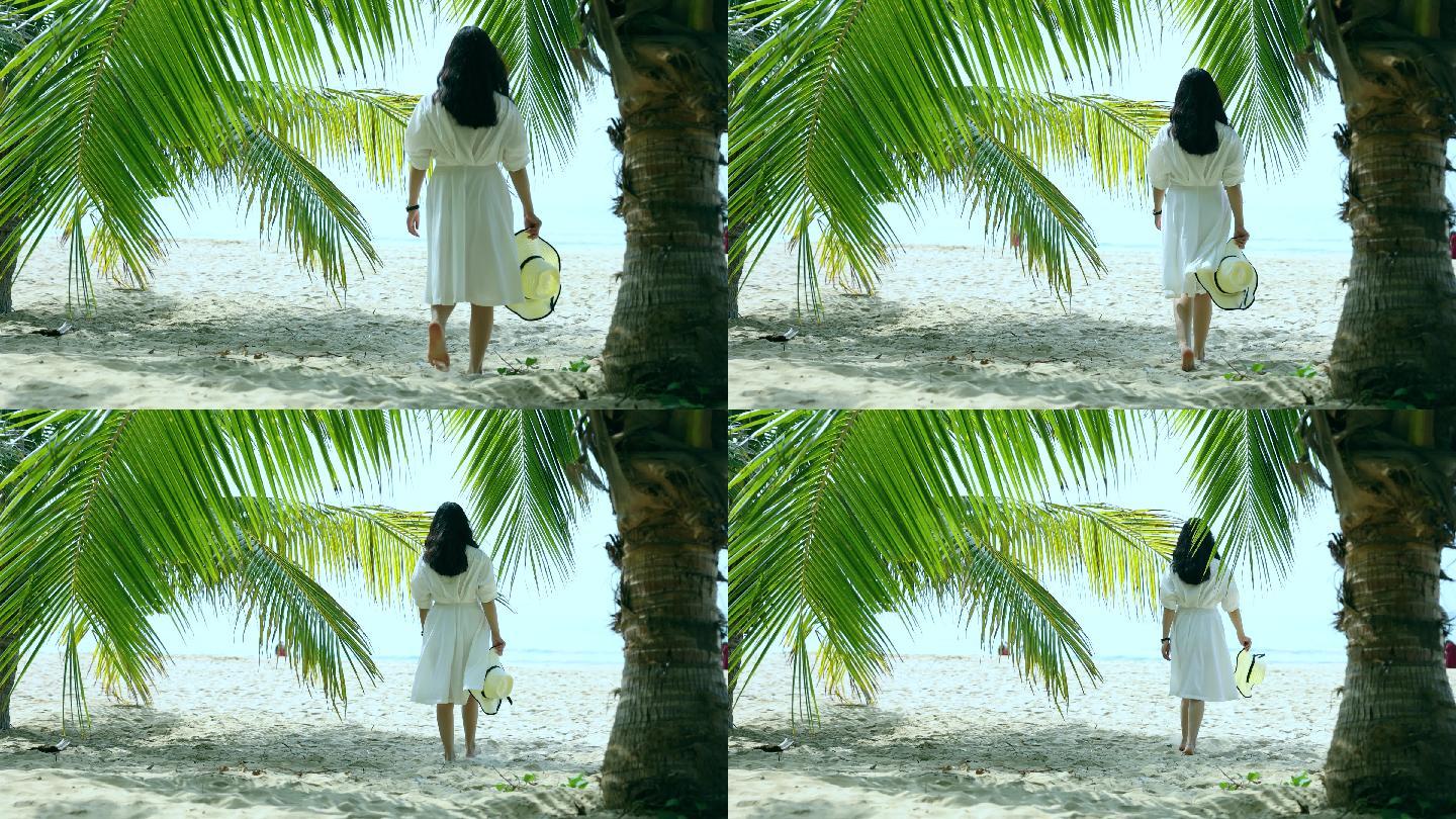 海滩上椰子树下走向大海的女人