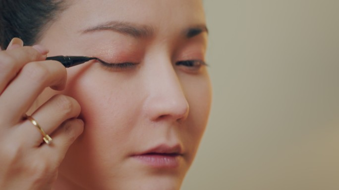 特写：亚洲女性化妆影响者使用眼线笔教程病毒内容记录化妆技巧
